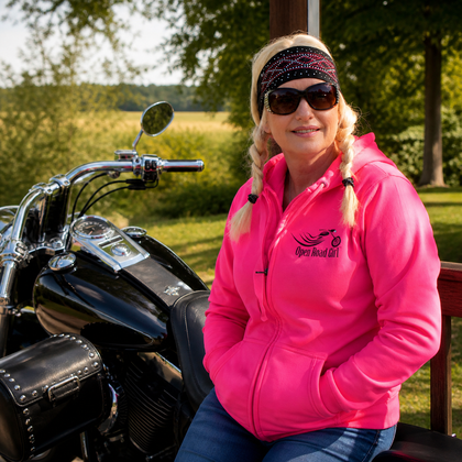 Woman wearing pink Open Road Girl hoodie standing by motorcycle – International Female Ride Day women riders lifestyle